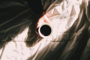 holding coffee in one hand in bed